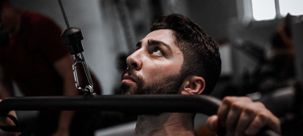 Muscular man working out with determination on gym equipment.